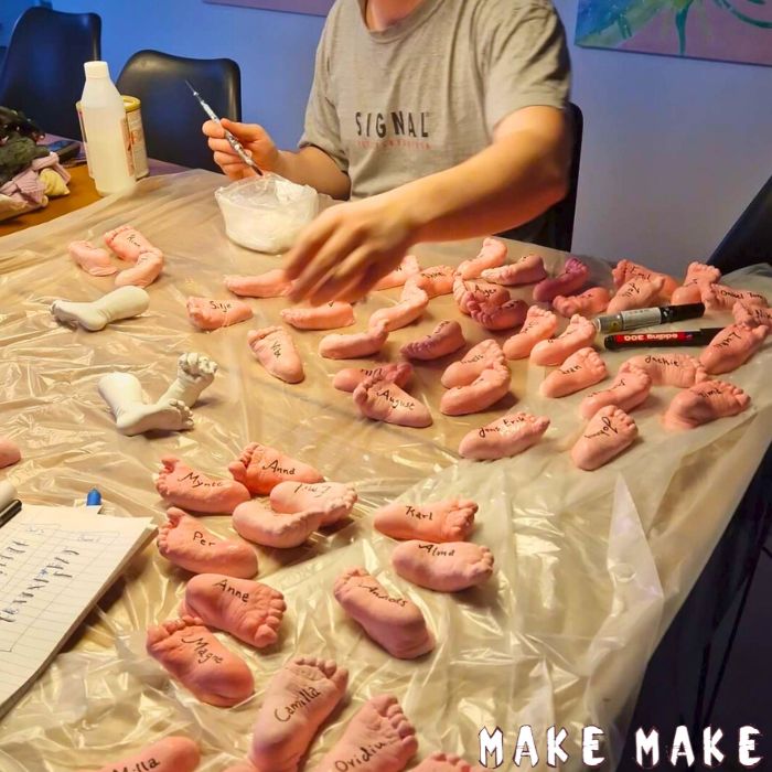 En masse fodaftryk i gips indfarvet lyserd med navne p til bordkort til barnedb.